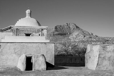 Two buildings at the Mission San José de Tumacácori in Southern Arizona. The building with brick and textured plaster walls stand in contrast to the mountain landscape. The curvature of the mission’s dome is echoed by the mountain’s dome. Absent of color, this black and white image relies on geometric shapes, texture, and tonal gradation for its visual statement.