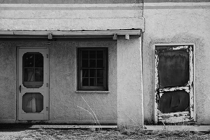 An image of an old vacated building in New Mexico (Fort Bayard near Silver City). Rich texture, simple planes and shapes, rendered in shades of grey. The building creates an image that takes one back in time and whispers stories of the past.